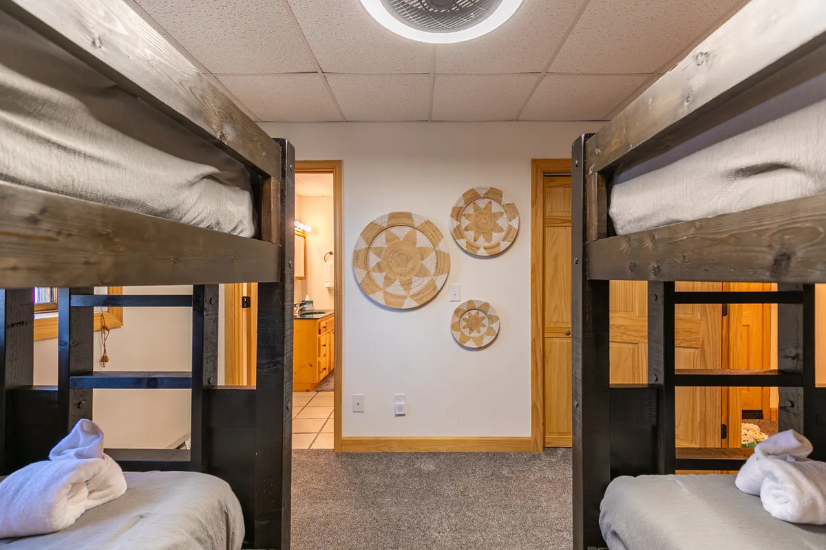 A playful bunk room with built-in bunk beds and decorative touches offers kids and families a welcoming spot to unwind after a day of mountain adventures. The space is bright and cozy, perfect for sharing stories, arcade games, or movie nights.