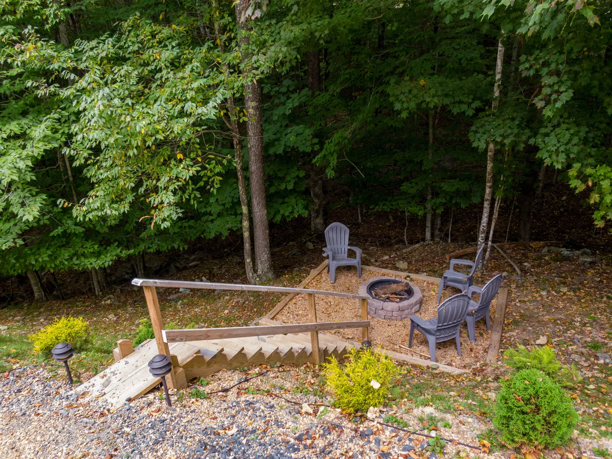 A cozy fire pit surrounded by comfortable seating is set in a wooded area, illuminated by the warm glow of the fire. The natural surroundings provide the perfect backdrop for stargazing, storytelling, and sharing s’mores under the stars after a day of adventure.