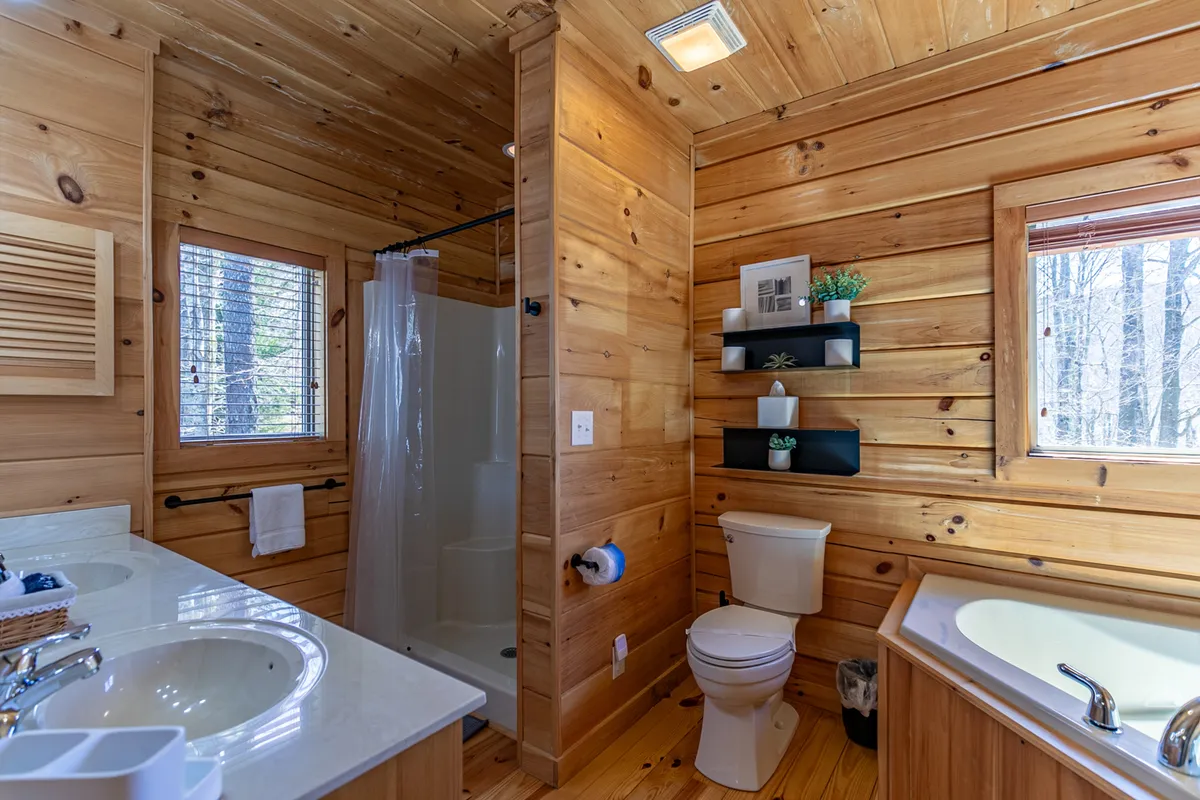 A tranquil bathroom with a deep soaking tub positioned near a window, inviting guests to relax while enjoying the views. Wooden paneling and soft natural light create a spa-like retreat.