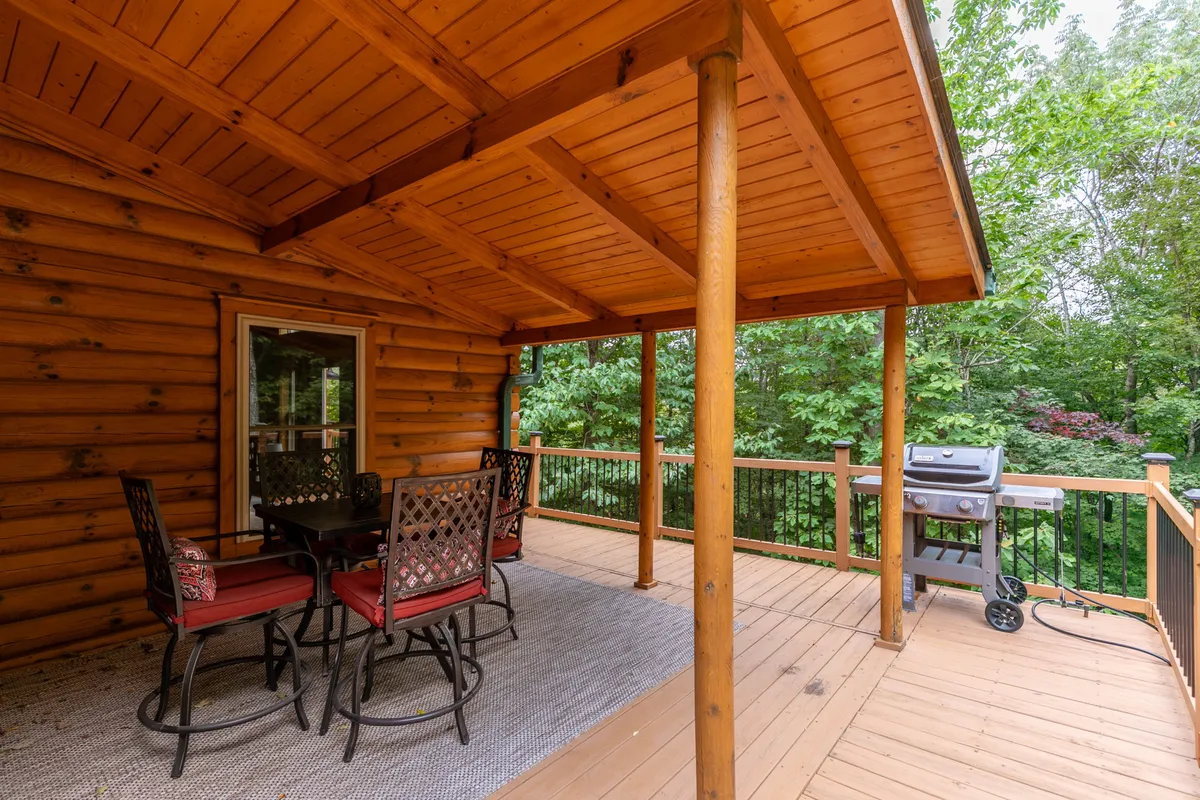 A cozy wooden deck features outdoor seating and a grill, positioned for both social gatherings and quiet moments. The arrangement highlights the opportunity for open-air dining, barbecues, and unwinding while taking in sunset views or starlit nights.