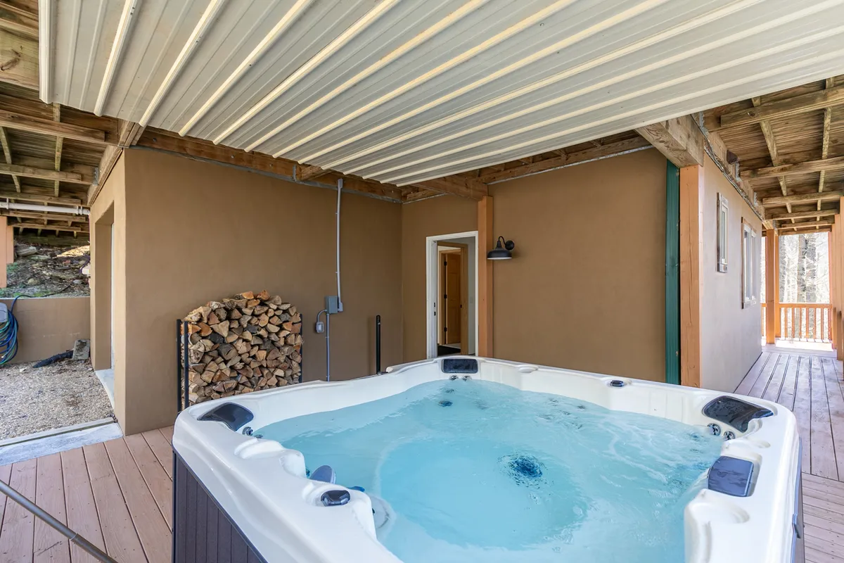 This image captures the inviting outdoor hot tub, framed by a stack of firewood and warm evening lighting. The space suggests relaxation and socializing, with the promise of stargazing or unwinding after an action-packed day.