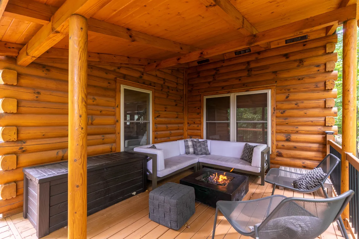 This image displays the exterior log cabin structure, an outdoor seating area, and a fire pit setup. It radiates a cozy, welcoming feeling—perfect for sipping coffee at sunrise, relaxing during the day, or gathering with friends for marshmallow roasting by night.